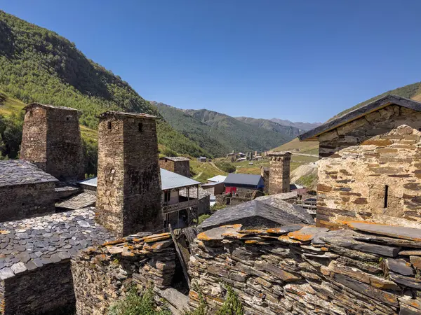 Stock image Traditional Svaneti towers standing tall amidst a village nestled in a lush green valley. Surrounded by mountains, these historic structures are a testament to the regions architectural heritage.