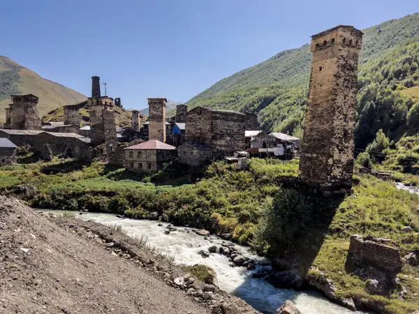 Stock image Traditional Svaneti towers standing tall amidst a village nestled in a lush green valley. Surrounded by mountains, these historic structures are a testament to the regions architectural heritage.