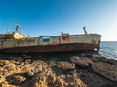 A close-up view of a rusty shipwreck resting on rocky shores with the open sea in the background, showcasing decay and maritime history. Paphos, Cyprus - October 28, 2024. clipart