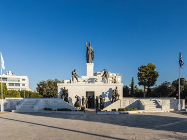 A grand monument featuring detailed statues, symbolizing history and heritage, surrounded by a clear urban backdrop and national flags. Nicosia, Cyprus - October 26, 2024. clipart