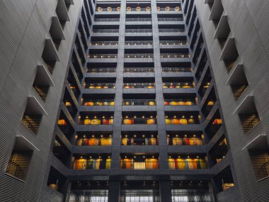 Modern mimari: Çağdaş, yüksek katlı bir binanın iç görünümü çok sayıda renkli kapılı balkon sergiliyor. Geometrik tasarım ve ışıklandırma çarpıcı bir görsel yaratıyor..