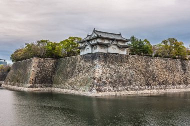 Tokyo 'daki Doğu Bahçesi İmparatorluk Sarayı' ndaki tarihi Edo dönemi yapısı. Antik taş duvarlar ve geleneksel bir Japon kale binası hendeğin durgun suyunu yansıtıyor. Huzurlu ve zamansız.