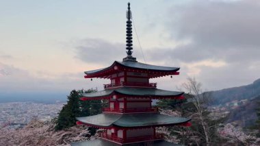 Japonya 'da üç katlı bir pagoda' dan Fuji Dağı 'nın sakin gündoğumu manzarası. Önünde kiraz çiçekleri var. Görkemli yanardağ kısmen sisle kaplanmış, güzel bir manzara yaratıyor..