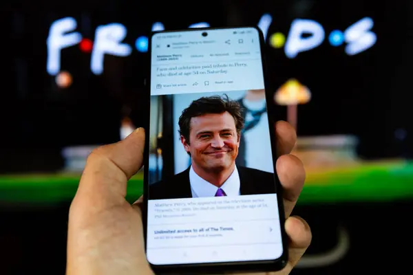 stock image Belgrade, Serbia - OCTOBER 30, 2023: Watching news on the smartphone about death of famous Hollywood star Matthew Perry who tragically passed away in his home in LA. He was best known for his role as Chandler Bing in popular tv show Friends  