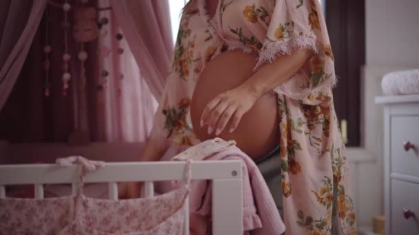 妊娠中の白人女性は新生児を計画するための折り畳みベビー服を準備する 子供部屋では 母親は出産を期待して待っています 新しい家庭の未来です 産前概念 — ストック動画