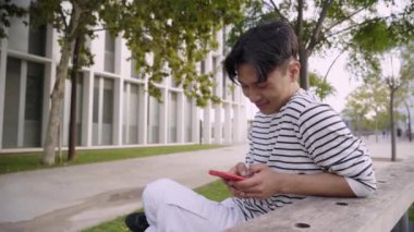 Üniversite kampüsündeki komik Asyalı adam bankta oturmuş akıllı bir telefonla sohbet ediyor. Öğrenci cep telefonu kullanıyor ve dışarıda gülüyor. Sosyal medyada sosyalleşen neşeli insanlar milenyum nesli