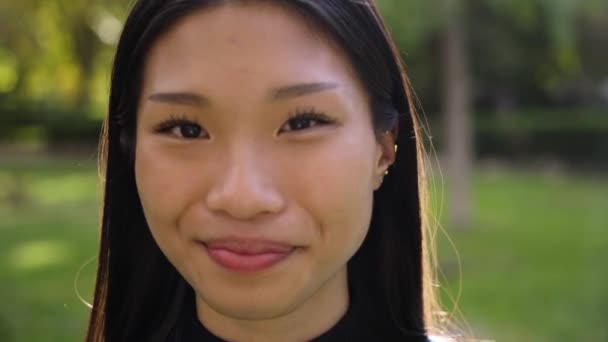 年轻美丽的亚洲女人的画像 微笑着看着外面的相机 前面看到的是快乐的中国女孩 羞怯的人在户外积极的情绪 — 图库视频影像