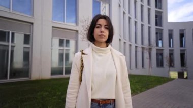 Kendine güvenen, resmi giysili genç Hintli bayan kollarını kavuşturup kameraya ciddi bir yüz ifadesi takınıyor. Sokaktaki insanlar, finans merkezi binalarında modern yöneticinin portresini yapan iş kadınlarının mutlu olduğunu düşünüyor.