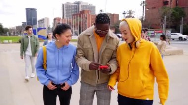 Okul dışında cep telefonu kullanan bir grup mutlu öğrenci eğleniyor. Üniversite kampüsündeki kızlar ve erkekler