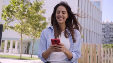 Açık havada cep telefonu kullanan genç bir kız. Uygulamayla flört eden gülümseyen bir kadın. İnternet üzerinden insan ilişkilerinin yeni çağında flört sitesi.