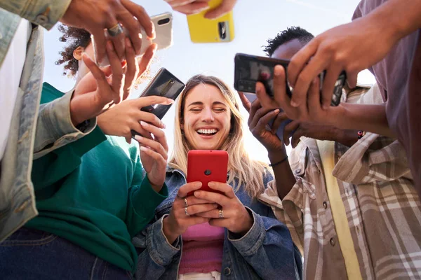 Bir grup genç arkadaşın cep telefonlarını kullanıp şehirde dolaşırken düşük açılı görüntüsü. Teknolojiye bağımlı bin yıllık toplum kavramı. Sosyal Medya İletişim Üretimi Z