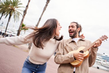 Komik mutlu ve sevgi dolu çift sokakta dans edip şarkı söylüyor ve gitar çalıyor. Erkek ve kadın şehirde tatillerinde eğleniyorlar. Yüksek kalite fotoğraf