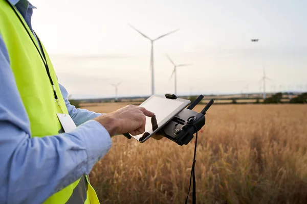 Operator holding remote control and quadcopter. Unmanned aerial copter starting in wind field. Male operating a drone using a remote controller. Engineer playing with drone renewable energy control