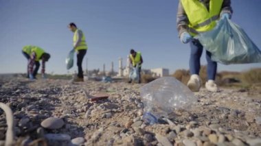 Bir grup temizleme gönüllüsü doğadaki atıkları temizliyor ve bir çöp torbasını tutuyorlar. Plastik bir şişeyi eline alan aktivist elini kapat. Çevre koruma kavramı.