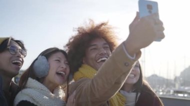 Neşeli bir grup arkadaş kış kıyafetleri giyerek selfie çekiyorlar. Sosyal medya iletişimi