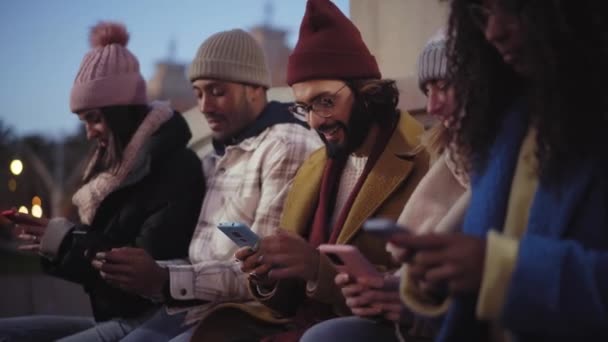 一群年轻的混血种族朋友与手机 科技成瘾者晚上在户外用手机 社交媒体连接的概念 嬉皮士 冬季时间 — 图库视频影像
