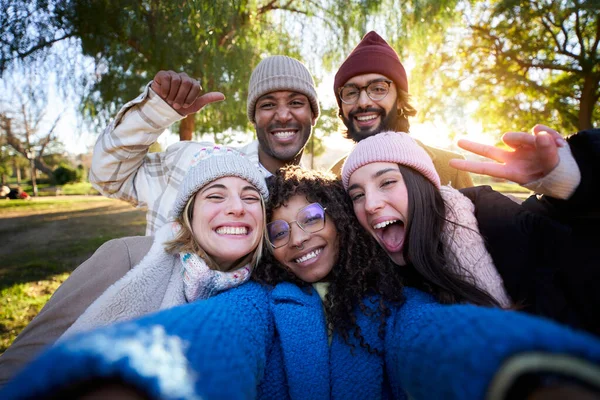 Winter time smiling selfie of a happy group of multicultural friends looking at the camera. Portrait of cheerful multi-ethnic young people of diverse races having fun together. Colleague hanging out.