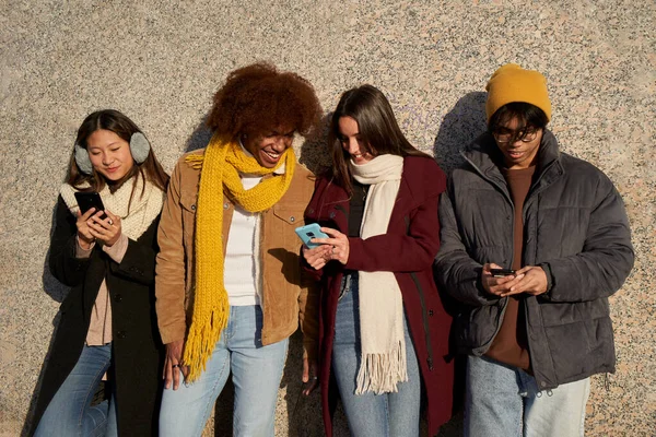 Group of young people using smart mobile phones app. Teenagers addicted to technology trends. Concept of youth, tech, social and friendship. University students and Social media online community.