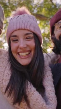 Vertical video of Multiracial people together looking camera in a selfie laughing - Group of mixed race friends having fun together at park - Friendship and lifestyle concepts