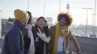 Side view of a group of excited young friends having fun together outdoor. Diverse people hugging and laughing enjoy. Youth culture concept