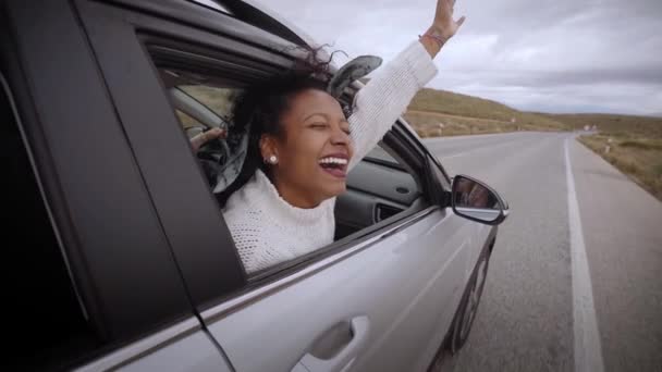 車の窓にラテン語の笑顔の女性 自動車旅行 風の中で冷たい髪 女の子は窓から外を見る 二次道路で車からの眺めを楽しむ若い女性 スローモーション — ストック動画