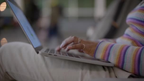 駅に座っている間にノートパソコンのキーボードを入力している若い女性のクローズアップショット 待ち時間の概念 女性は空港出発ラウンジで彼女のコンピュータを使用して — ストック動画