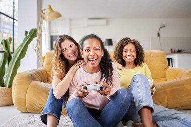 Bir grup genç bayan çok ırklı genç arkadaş evde video oyunları oynuyorlar. Sadece kadınlar oynar ve patlamış mısır yer. - Evet. Yüksek kalite fotoğraf