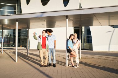 Group of friends standing on the university campus using their phones. High quality photo
