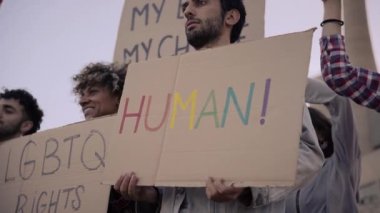 Göstericiler pankart tutan bir grup protestocu. Gay gururlu LGBT topluluğu. Gökkuşağı bayrağı.