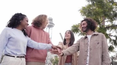 Group of young entrepreneur team stacking hands outdoors and looking at the camera. High quality photo