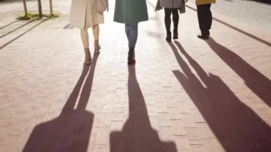 Feet of four unrecognizable faceless people walk outside on a sunny day in a corporate business district. High quality 4k footage