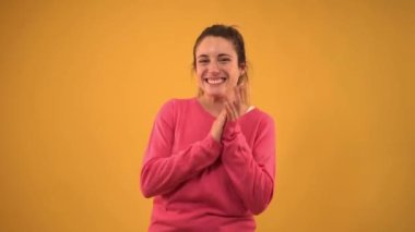 Young girl clapping and smiling enthusiastically after presentation at a conference on isolated background. Yellow screen with chroma key. Cheerful blonde woman applauding and celebrating a success.