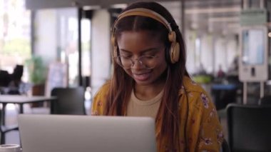 Video Young black African college girl studying online on her laptop. Smiling applied Latina woman taking online virtual class sitting in campus cafeteria. Closeup happy woman concentrating.