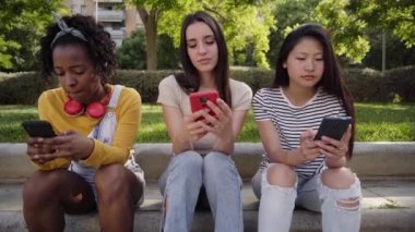 Dışarıda cep telefonu kullanan üç ciddi kadın. Grup konsantre olmuş arkadaşları akıllı telefondan sosyal ağları kontrol ediyorlar. Meslektaşlar cep telefonlarındaki son notlara bakıyor. Genç kız teknolojisi bağımlısı 