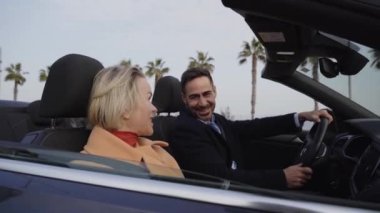 A happy middle-aged couple gets out of the car to go to their appointment. The wife and husband unbuckle their seat belts, open the door and close it. Concept of relationship, weekend and leisure.