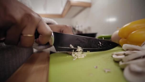 Zbliżenie Młodych Czarnych Rąk Dziewczyny Cięcia Czosnku Nożem Desce Drewnianej — Wideo stockowe