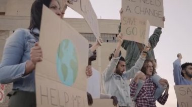 İklim değişikliğini protesto eden bir sokak protestocusu için afiş toplamama yardım et. Ağır çekim. Yüksek kaliteli FullHD görüntüler