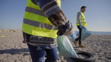 Bir çift temizleme gönüllüsü doğada atık topluyor ve ellerinde çöp torbaları tutuyor. Siyahi kız aktivistin plastik topladığı yakın plan. Çevre koruma kavramı.