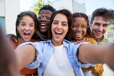 Selfie young excited friends looking at camera happy. Smiling Group of people having fun together outdoors. Crazy community of college students. Modern lifestyle of multicultural people.