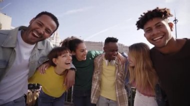 Kameraya bakarak selfie için poz veren ve gülümseyen gençler. Bir grup çok kültürlü erkek ve kız dışarıda tatilin bitmesini kutluyorlar. Boş zaman, arkadaşlık..