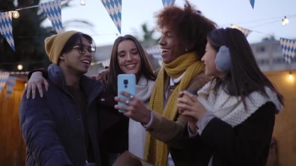 由四个朋友组成的快乐微笑的多民族团体为社交媒体拍摄户外视频 情侣们在冬节晚会上聚会 快乐的人在网上用手机与同事联系 — 图库视频影像