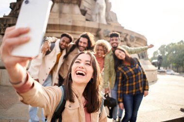 Üniversite kampüsünde neşeli bir grupla dışarıda gülümseyen bir selfie çeken bir kadın. Yüksek kalite fotoğraf