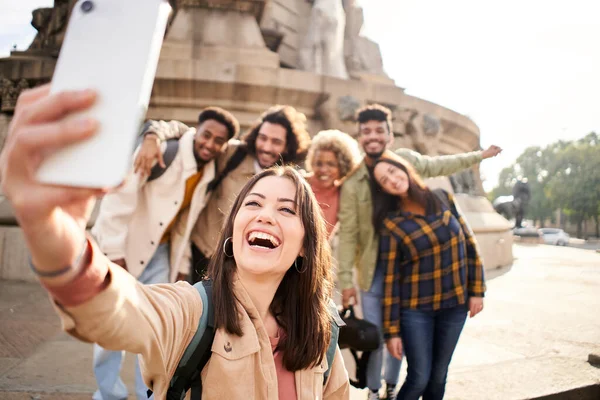 Woman with a cheerful group of college of university campus taking a smiling selfie outdoors. High quality photo