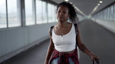 Havaalanında ya da tren istasyonunda yürürken telefonla konuşan ve gülümseyen genç bir kadın yolcu. Güzel Latin kızın cep telefonu var, elinde bavul var.. 