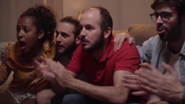 Beyaz, neşeli, mutlu, genç arkadaşlar. Kadın ve erkek evde takılıyor, favori takım için tezahürat yapıyorlar ve maçı kazanıyorlar. Spor kanalında insanlar maç izliyor, eğlenceli bir konsept.