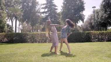 Genç, çok kültürlü, stil sahibi kızlar hip hop yapıyor, açık havada sokak dansı yapıyor. İki güzel kadın bahar günü parkın çimlerinde koreografi gösterisi yapıyor. Halk gençlik alt kültürü. 