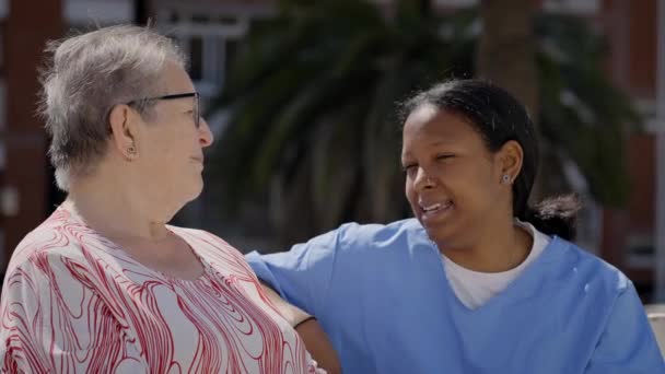 Emerytka Czatuje Szczęśliwie Młodą Latynoską Pomoc Domową Świeżym Powietrzu Starsza — Wideo stockowe