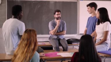 Sakallı ve gözlüklü kendine güvenen öğretmen okuldaki bodur öğrencilere ders veriyor. Genç erkek stajyer öğrencileriyle konu hakkında sohbet ediyor. Üniversiteliler özel derste..