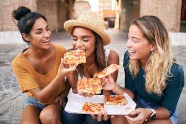 Üç kızdan oluşan komik bir grup ve turistik şehirde pizza yerken eğleniyorlar. İtalyan kadın sokak yemeği yiyor. Yüksek kalite fotoğraf