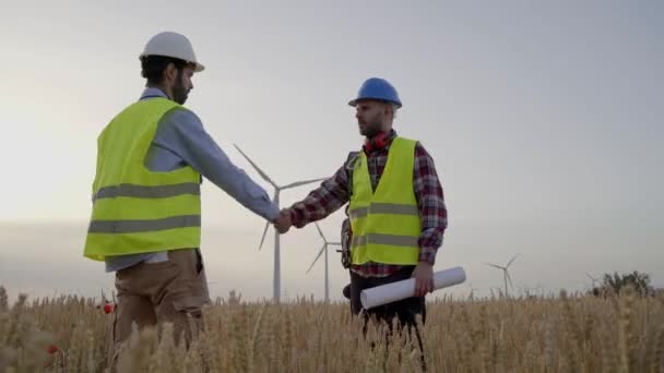 工程师和技术人员握手 在农田风力涡轮机上实施新的可持续发展项目 专业技术人员在风电场外工作 清洁可再生能源 — 图库视频影像